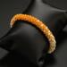 Orange Creamsicle Kumihimo bracelet by Bead & Braid Collective, handcrafted glass seed bead bracelet displayed on black cushion